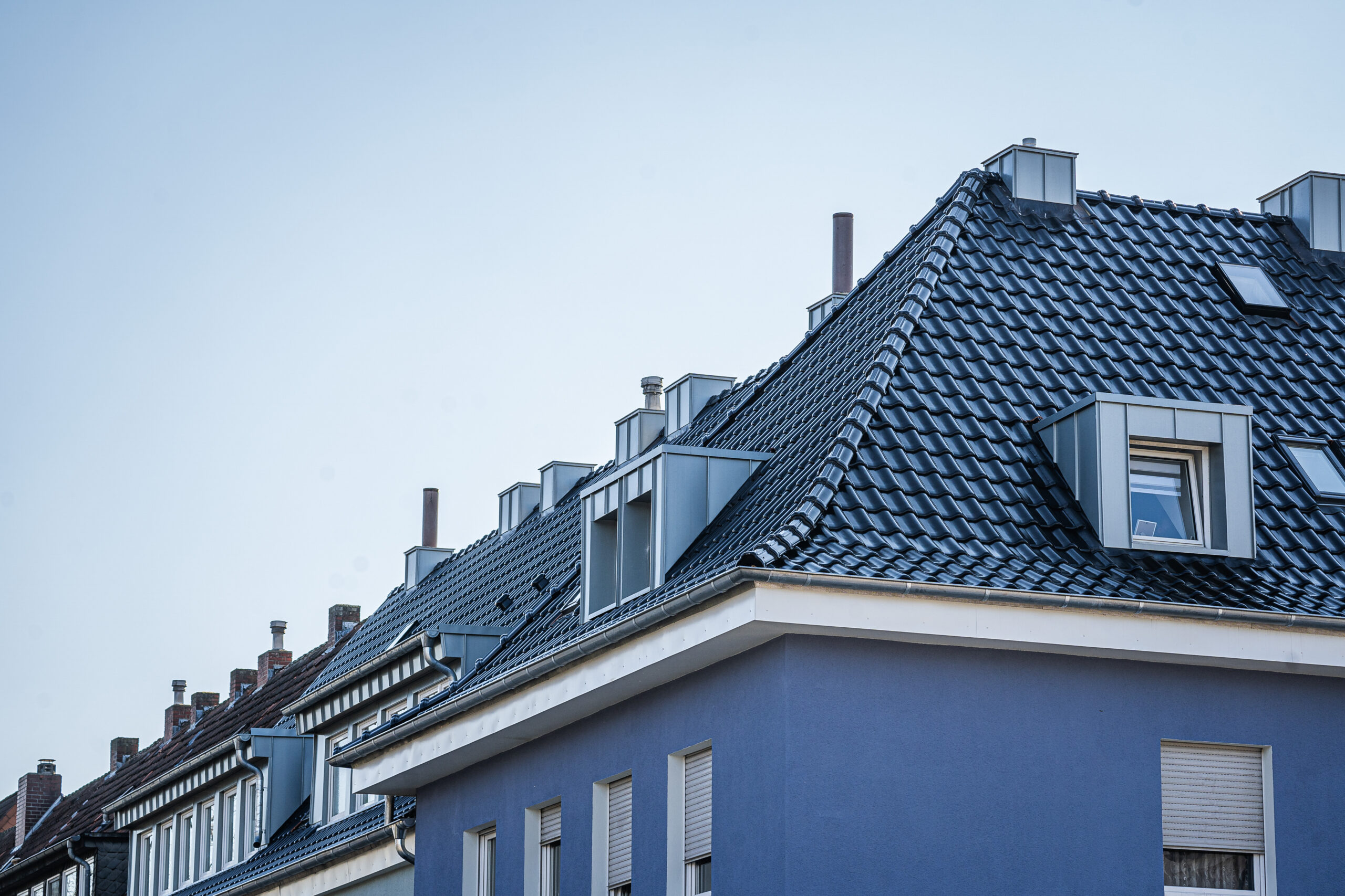 Mehrfamilienhaus mit Gauben und Tonziegeln auf dem Dach