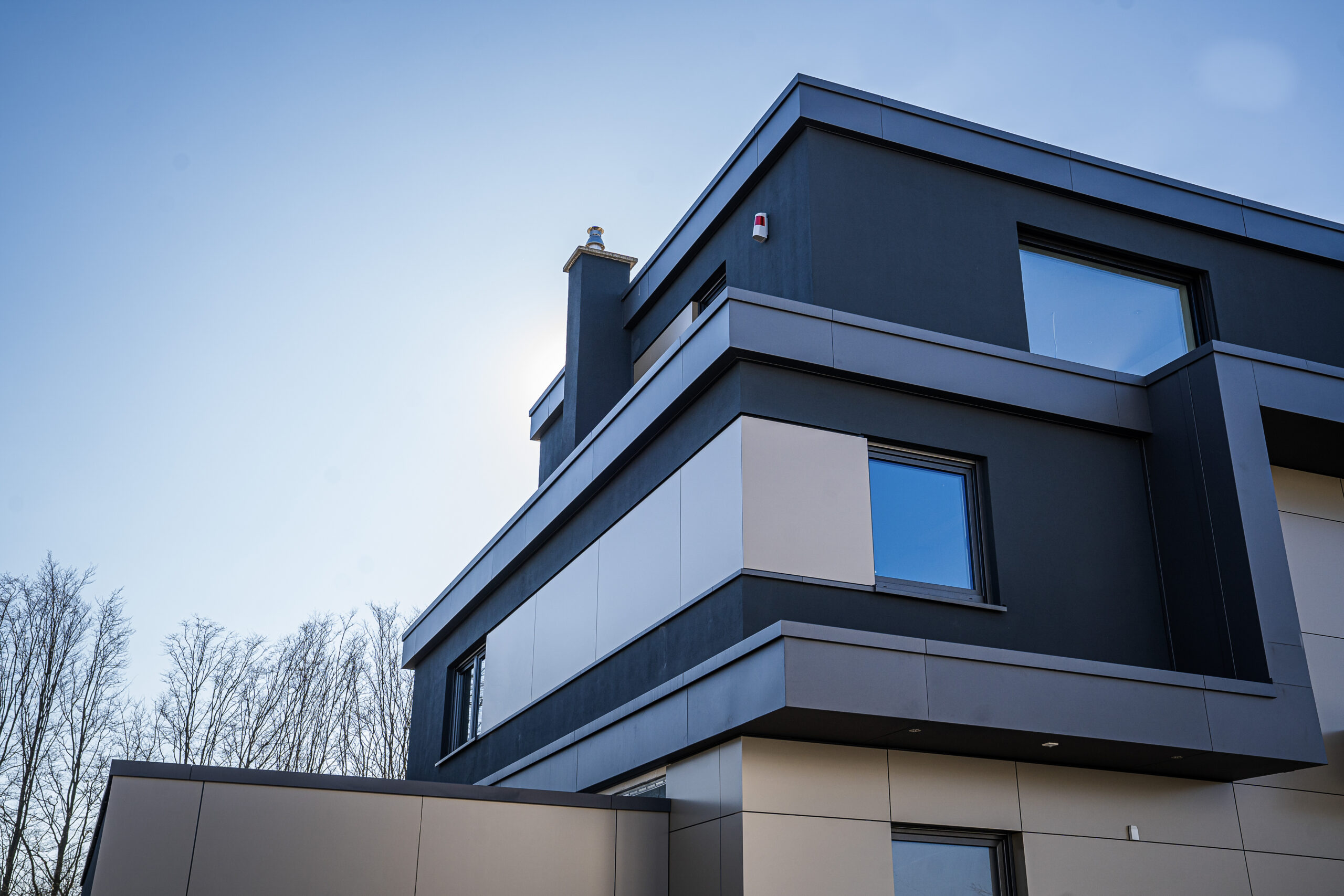 Flachdachhaus mit anthrazitfarbener Fassade und Attikaabdeckung